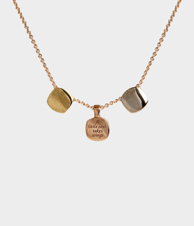 A rose gold necklace with three square shaped pieces in yellow, rose and white gold and a message saying 'a little soul takes wings' engraved in the middle square.